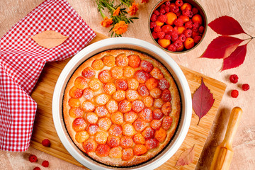 Homemade delicious sweet apricot pie served with raspberries on a table, top view
