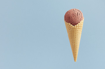 Chocolate ice cream in crisp waffle cone on pastel blue background, mock up for design, summer food.