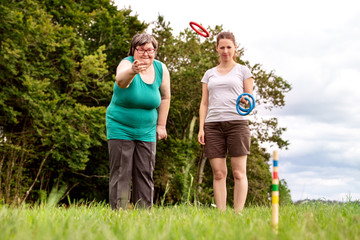 Geistig behinderte Frau und Betreuerin spielen zusammen Ringe werfen, Freizeit und Spiel