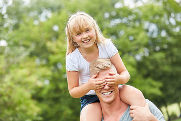 Mädchen hält ihrem Vater die Augen zu