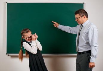 angry teacher shout to schoolgirl, posing at blackboard background - back to school and education concept