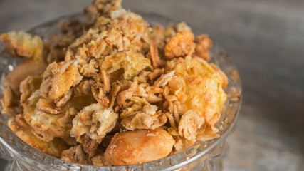 Flakes or granola in a glass bowl with nuts close-up, macro image.