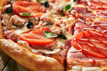 Pizza in half with chicken and mushrooms and greens, on other - with ham and sauce. On rustic...