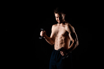 Fototapeta na wymiar A man on a black background with dumbbells in his hands. young bearded athlete.