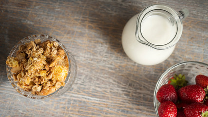 Milk cereal and ripe strawberries in a glass bowl overhead view. Close up of healthy food ingredients. Selective focus copy space. Healthy dessert.