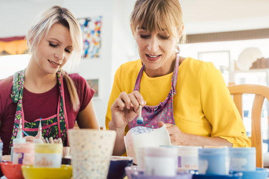 Women in DIY workshop coloring and decorating their own ceramic
