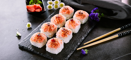 Delicious roll with masago caviar cap close up. Sushi bar, oriental cuisine restaurant menu item. Traditional asian snack, national cooking. Tasty eastern food, gourmet snack on wooden platter