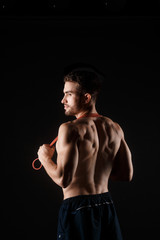 Fototapeta na wymiar sports man with a beard on a black background with gymnastic elastic bands in hands