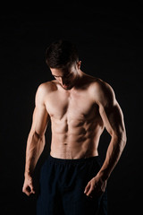 Naklejka na ściany i meble Young bodybuilder on a black background. Naked torso