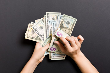 Businesswoman's hands counting five and other dollar bills on colorful background. Salary and wage concept. Top view of Investment concept