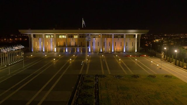 Knesset building the Parliament of Israel with flying waving flag of Israel at night