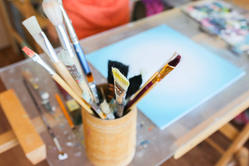 Real work studio of the painter. Man is creating picture. Artist concept. Creative atmosphere. Paint brushes.