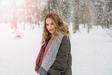 Christmas, New Year, winter holidays concept. Cute teenage girl with curly hair. playing with snow in park.