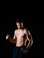 Fototapeta na wymiar A man on a black background with dumbbells in his hands. young bearded athlete.