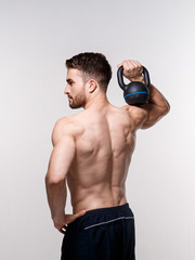 Fototapeta na wymiar Young athlete on a white background lifts a kettlebell. training a bearded man athletic build