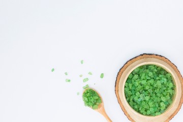 Green salt in wooden bowl and spoon on white background. Spa, healthcare, cosmetology concept. Top view, flat lay, copy space