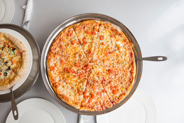 Pizza on iron tray on table in cafe. Top view, copy space