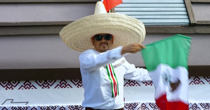 Hispanic mariachi musician in sombrero dances and waving flag at Mexican Independence Day parade in Los Angeles, California, 4k