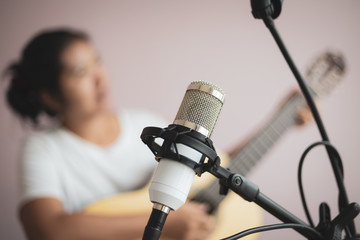 Asian woman play acoustic classic guitar for jazz and easy listening song and record with microphone select focus shallow depth of field and vintage tone processed