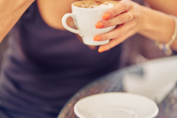 girl's hand holds a cup of cappuccino