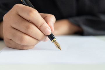Close up shot hand of business woman using the pen to write on the white paper select focus shallow depth of field