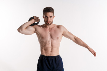 Young athlete on a white background lifts a kettlebell. training a bearded man athletic build