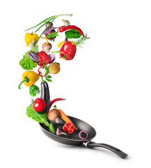 Cooking concept. Vegetables are flying out of the pan isolated on white background. Healthy food.