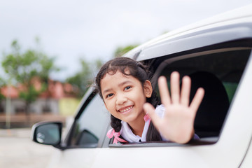 Portrait little Asian girl in Thai student kindergarten uniform smiling with happiness in the car select focus shallow depth of field