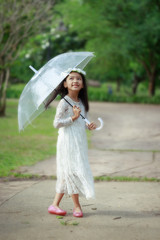 Little Asian girl holding clear umbrella and smiling with happiness select focus shallow depth of field