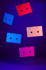 Colored audio cassettes hanging in the air against purple background