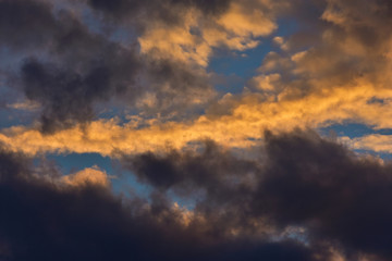 Sunset sky with golden and dark clouds as background