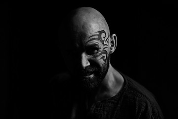 tattoo on the face,  man with a tattoo,  brutal bearded guy, studio portrait of a man