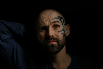 tattoo on the face,  man with a tattoo,  brutal bearded guy, studio portrait of a man