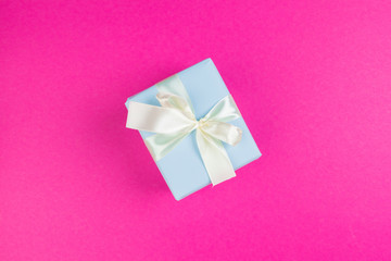 Top view of a decorated present with a bow on pink background