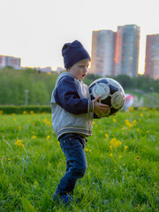 A small child in a cap playing on the grass with a ball.