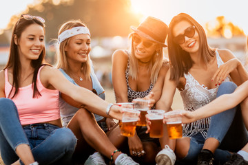 Female friends cheering with beer at music festival	