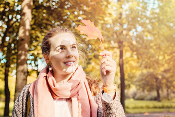 Naklejka premium Beautiful autumn woman holding yellow maple leaf outdoors. Roman