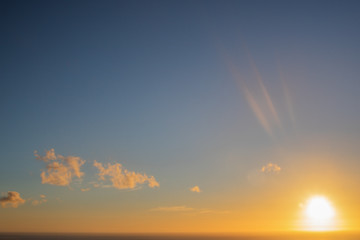 Sun setting over a golden blue sky over the ocean.