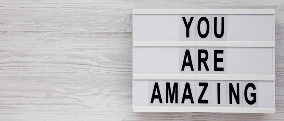 'You are amazing' words on a modern board on a white wooden surface, top view. Overhead, from above. Flat lay. Copy space.