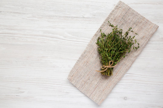 Raw organic fresh thyme on cloth on a white wooden background, top view. Flat lay, overhead, from above. Copy space.