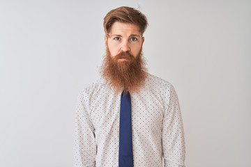 Young redhead irish businessman standing over isolated white background Relaxed with serious expression on face. Simple and natural looking at the camera.