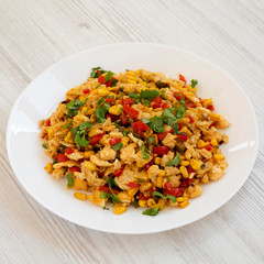 Homemade southwestern egg scramble on a white plate on a white wooden background, side view. Close-up.
