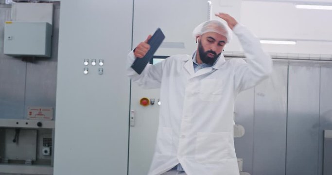 Very charismatic engineer man dancing excited while walking on his work place open the tablet and start to checking the machine