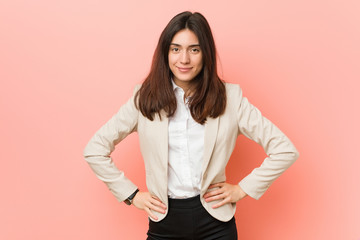 Fototapeta premium Young brunette business woman against a pink background confident keeping hands on hips.