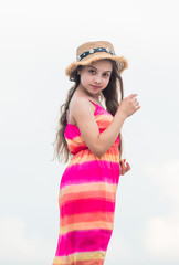 Obraz na płótnie Canvas Happy vacation. Enjoying relax. Child happy small girl. Free and carefree. Good vibes. Happy international childrens day. Happy childhood. Cute girl in summer dress and hat outdoors sky background