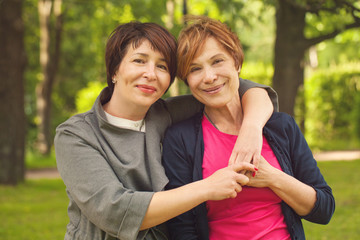 Two happy women walking in summer park, portrait