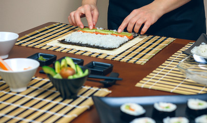 Chef hands placing ingredients on rice to make sushi © David Pereiras