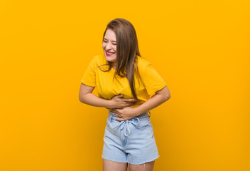 Obraz premium Young woman teenager wearing a yellow shirt laughs happily and has fun keeping hands on stomach.