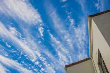 House with dramatic blue sky with streaks of vertical clouds.