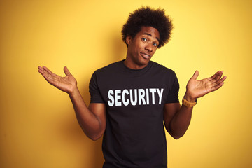 American safeguard man with afro hair wearing security uniform over isolated yellow background...